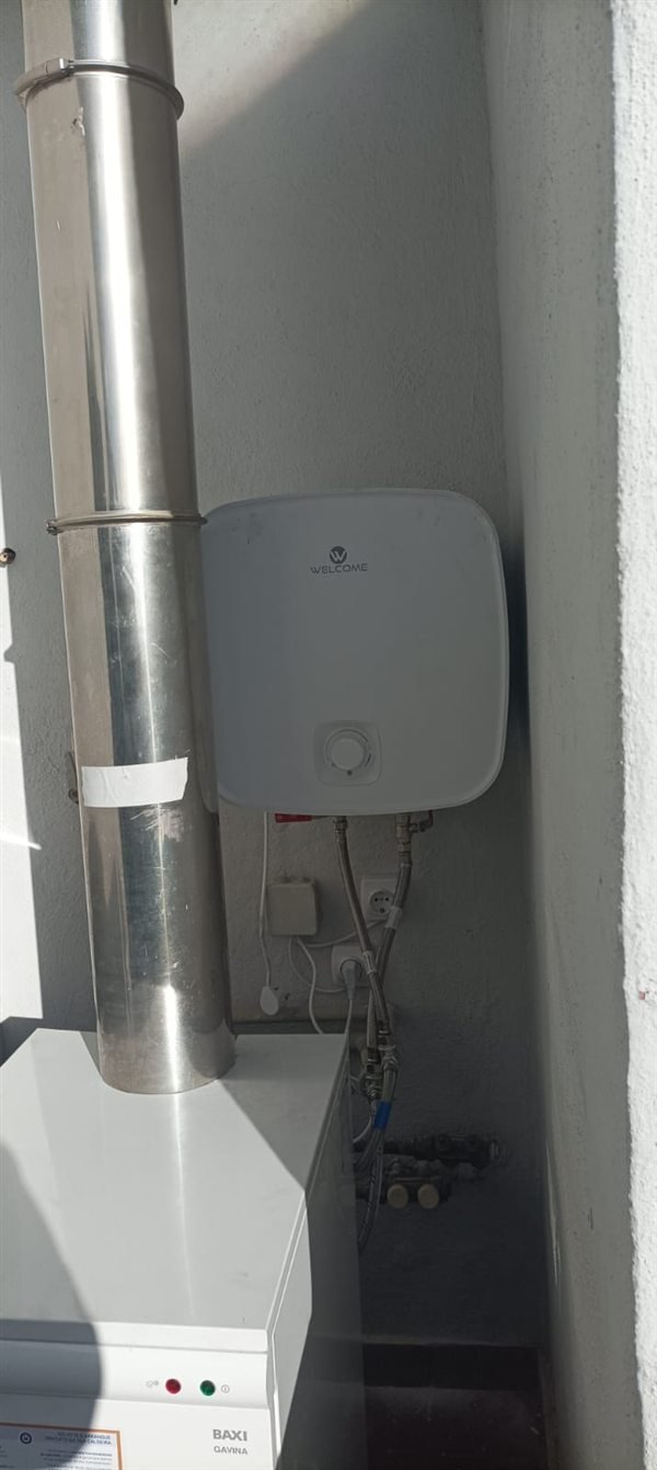 Caldera de gasóleo Baxi Gavina con su chimenea de acero inoxidable y termo eléctrico Welcome instalado en la pared, en una vivienda de Logroño